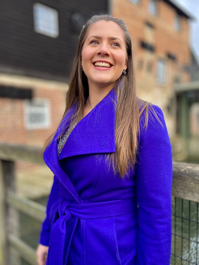 Cambridgeshire Contemporary Celebrant, Jemma wearing a long blue coat. She is smiling and cannot wait to create your ceremony